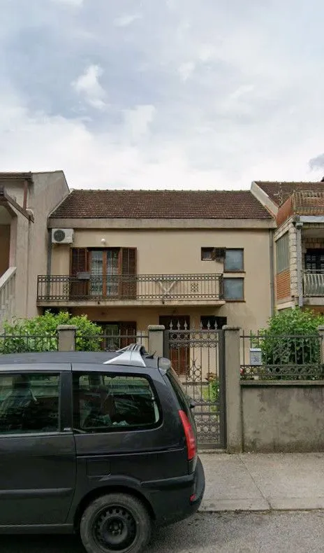 Spoljašnji izgled kuće sa dvorištem i balkonom.