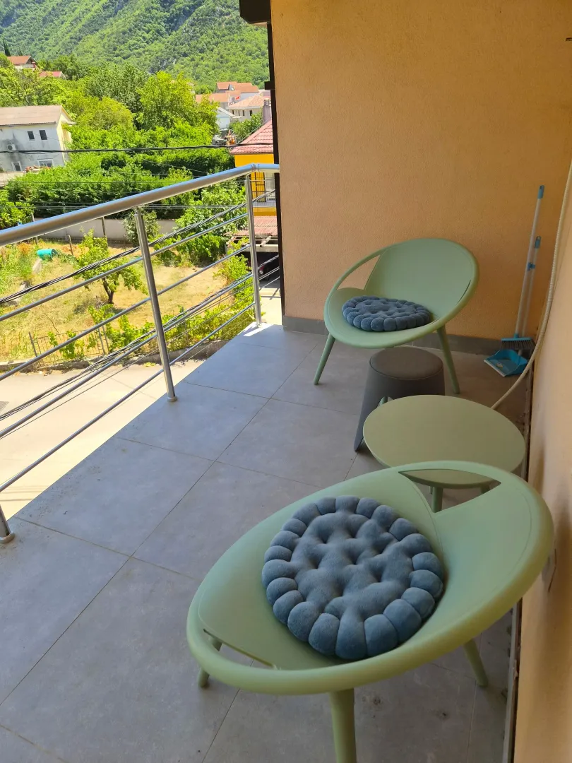 Furnished balcony with seating set and greenery view.