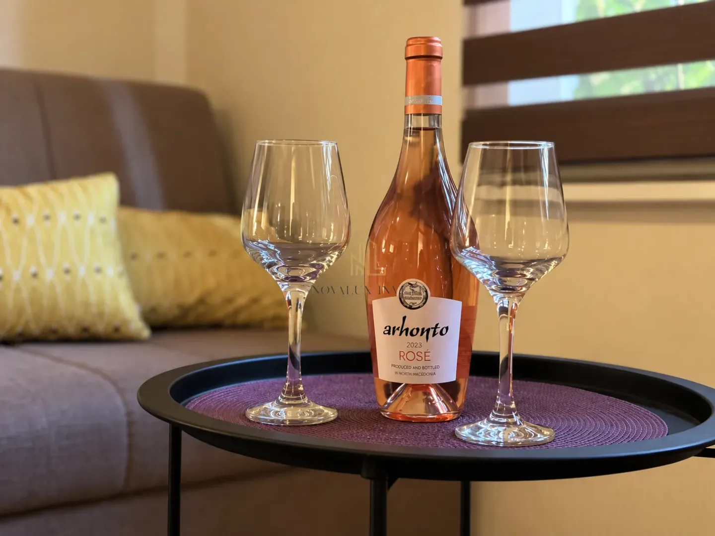 Flaša rosé vina i dvije čaše na stočiću u enterijeru.