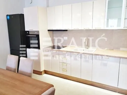 Modern kitchen with white units and a dining table.