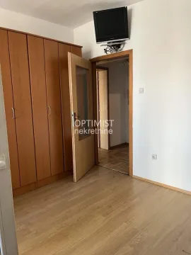 Spavaća soba sa velikim drvenim ormanom i televizorom na zidu. - image 4