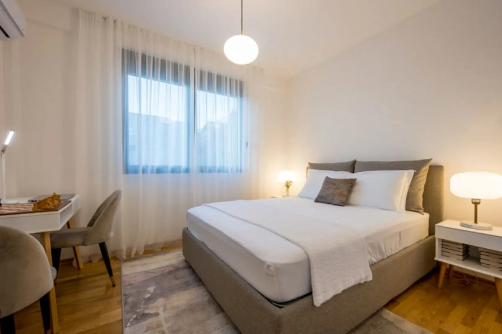 Moderna spavaća soba sa bračnim krevetom, radnim stolom i velikim prozorom.