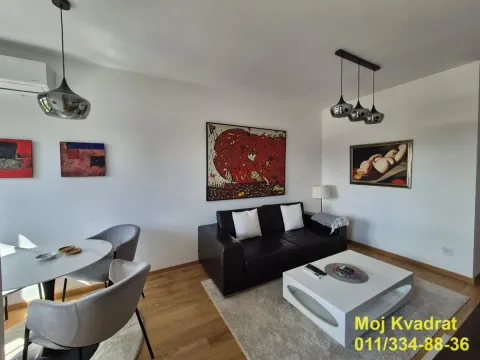 Dnevna soba sa garniturom, trpezarijskim stolom i umetničkim slikama na zidu. - image 3