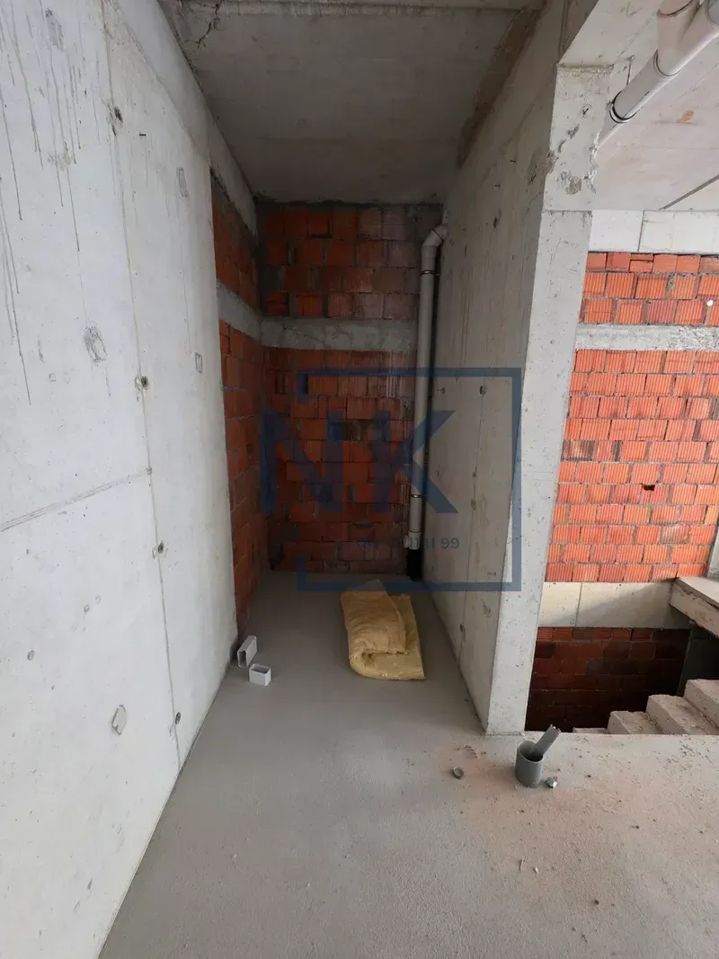 View of a property in a grey phase of construction with exposed brick and concrete walls.