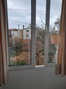 Pogled kroz prozor na okolne zgrade i drveće. - image 7