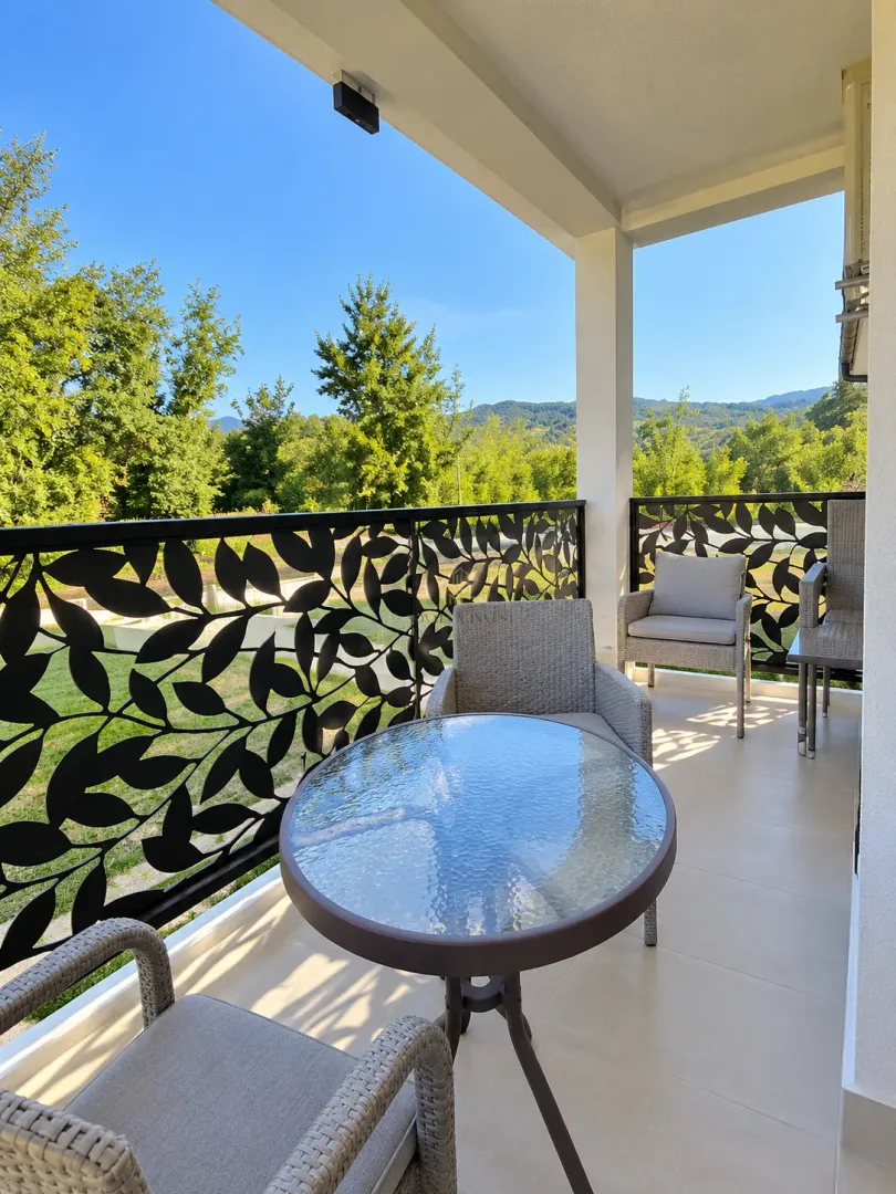 Covered balcony with outdoor seating furniture and nature view.