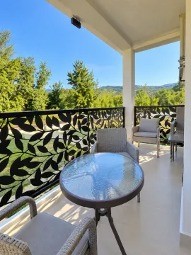 Covered balcony with outdoor seating furniture and nature view. - image 14