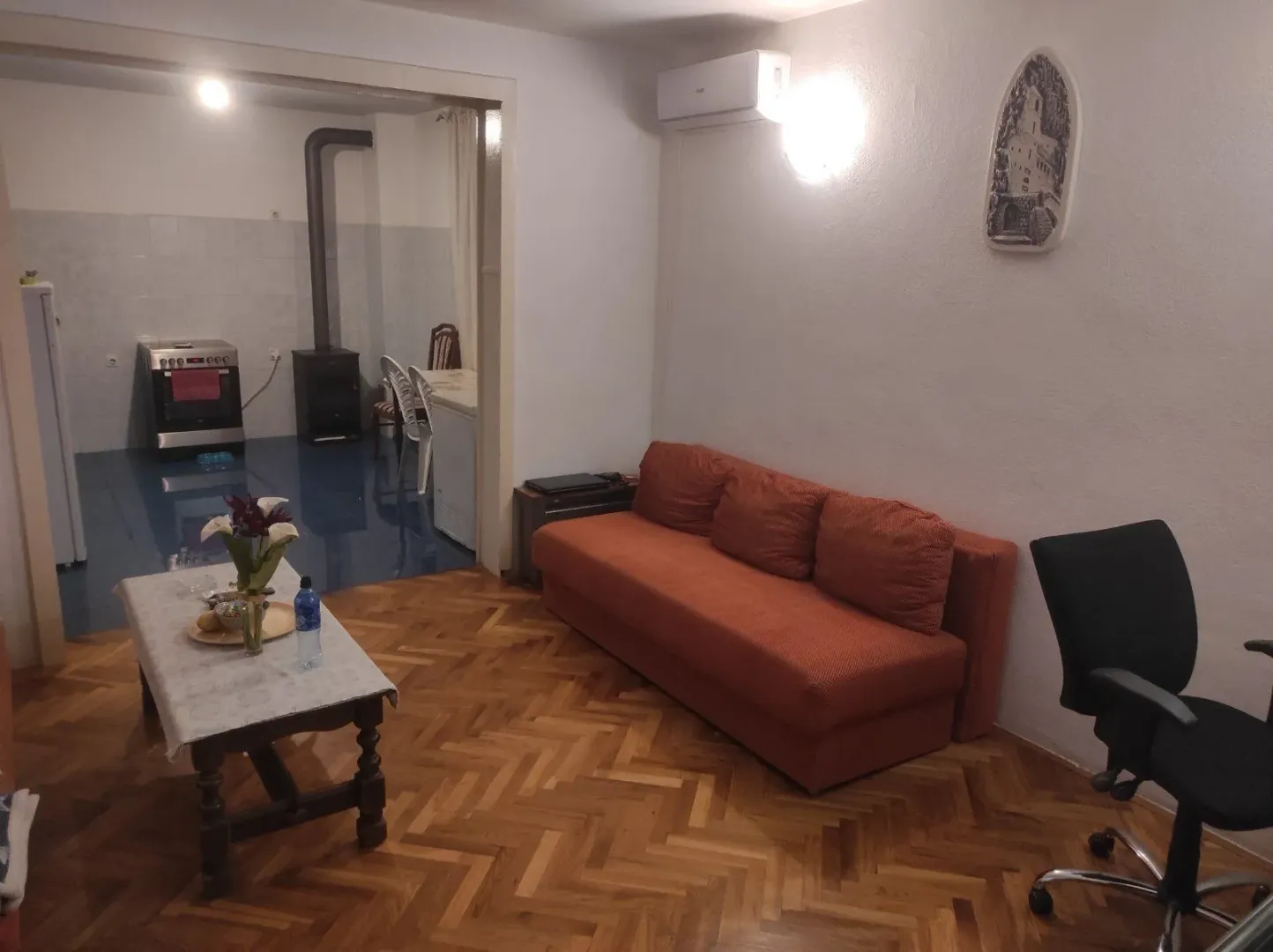 Living room with an orange sofa and a view towards the kitchen.