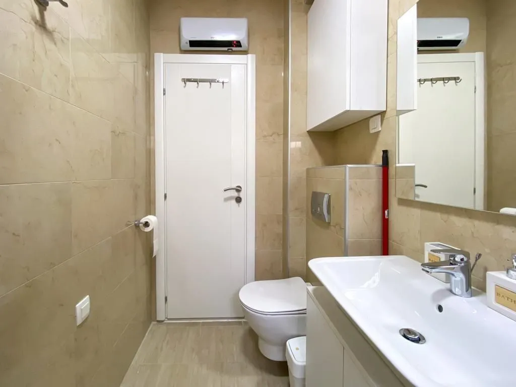 Smaller tiled bathroom with a washbasin and toilet.
