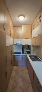 Uska kuhinja sa bež i bijelim elementima i sudoperom. - image 3