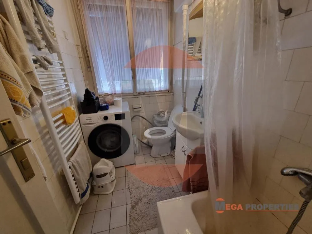 Smaller bathroom with a bathtub, washing machine, washbasin, and toilet.