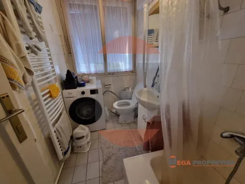 Smaller bathroom with a bathtub, washing machine, washbasin, and toilet. - image 11