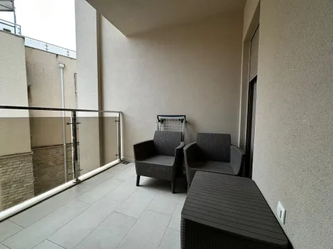 Covered balcony with seating furniture and a glass railing. - image 8