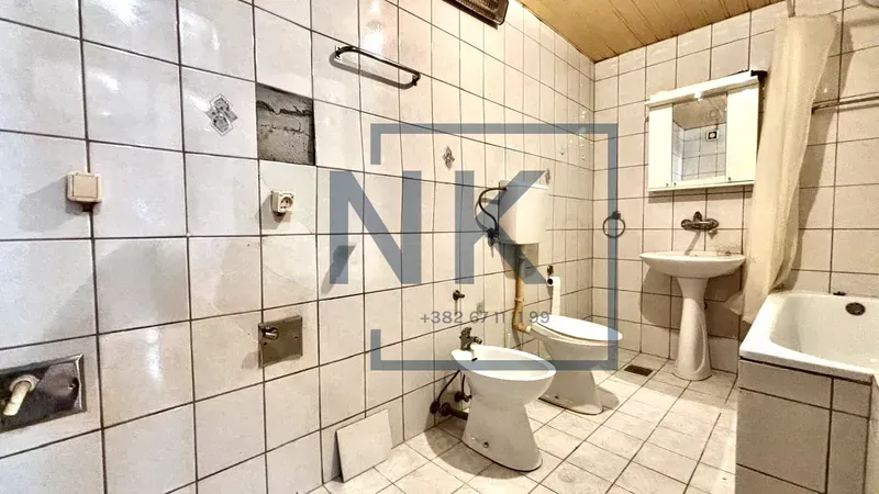 Starije opremljeno kupatilo sa kadom, umivaonikom i sanitarijama u izvornom stanju.