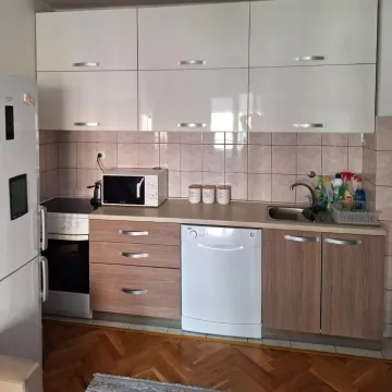 Small kitchen with white wall cabinets and wooden lower cabinets. - image 2