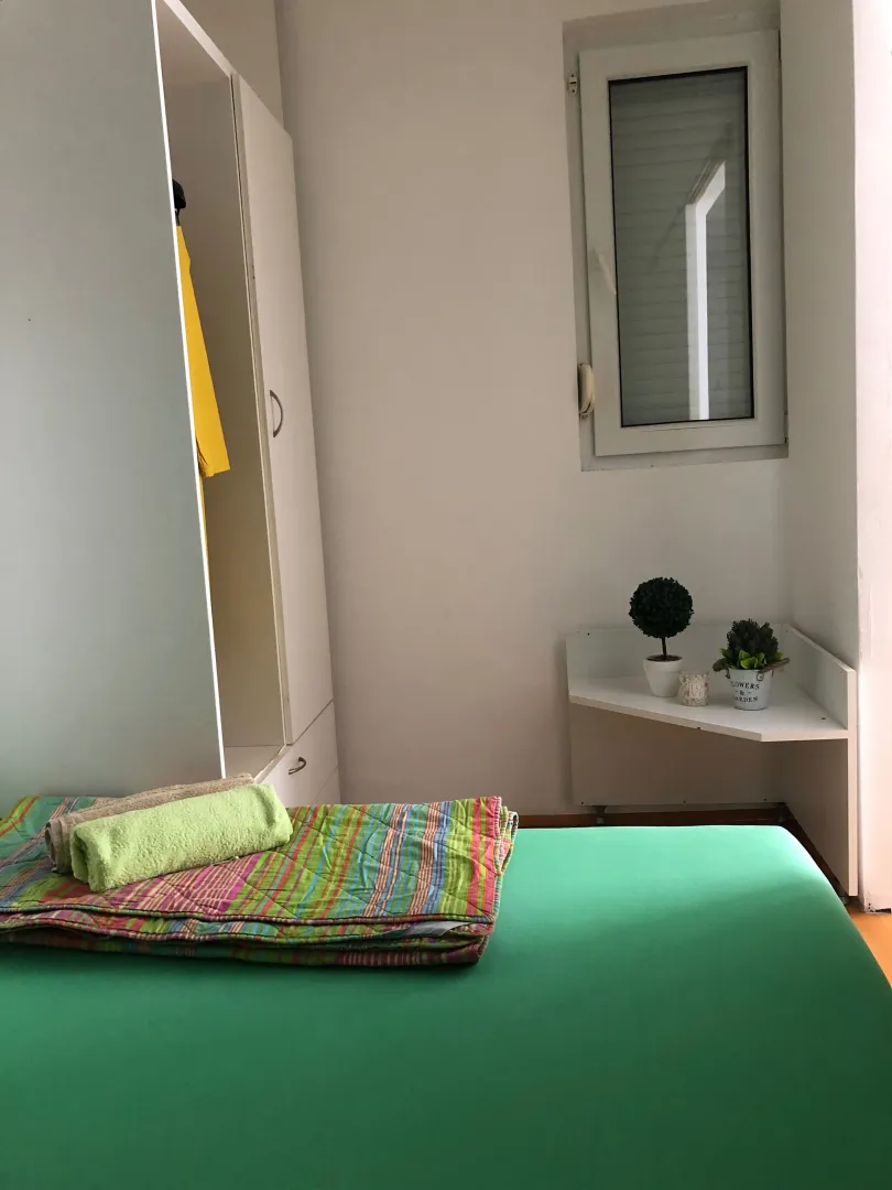 Small bedroom with a bed, wardrobe, and window.