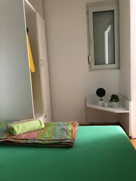 Small bedroom with a bed, wardrobe, and window. - image 10