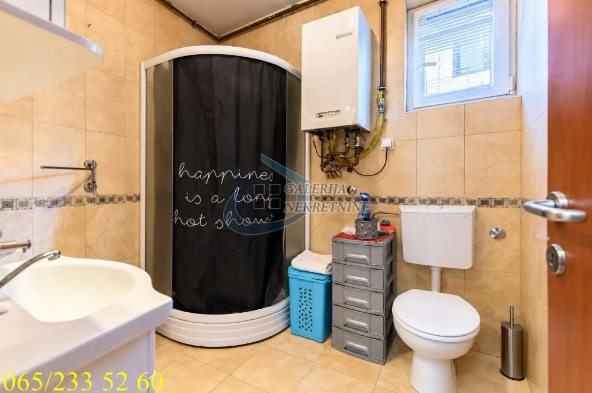 Kupatilo sa tuš kabinom, umivaonikom, WC šoljom i zidnim bojlerom.