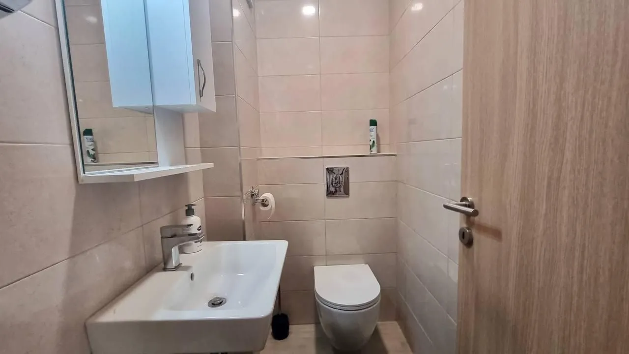 Small tiled bathroom with a sink and a toilet.