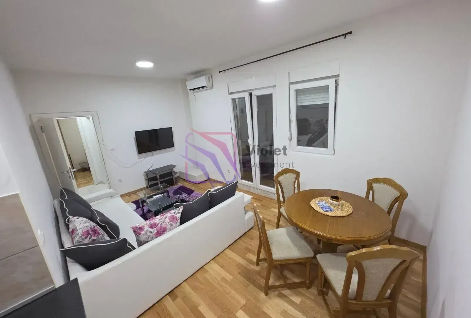 Living room with a sofa, TV, and dining table with chairs.