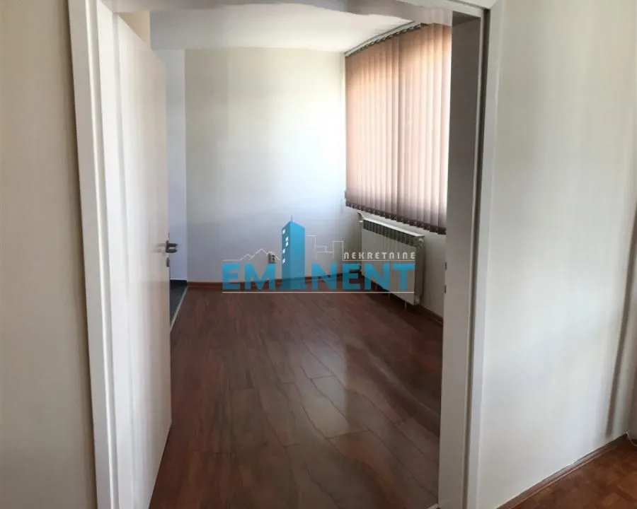 View from the hallway into an unfurnished room with wooden flooring and a window.