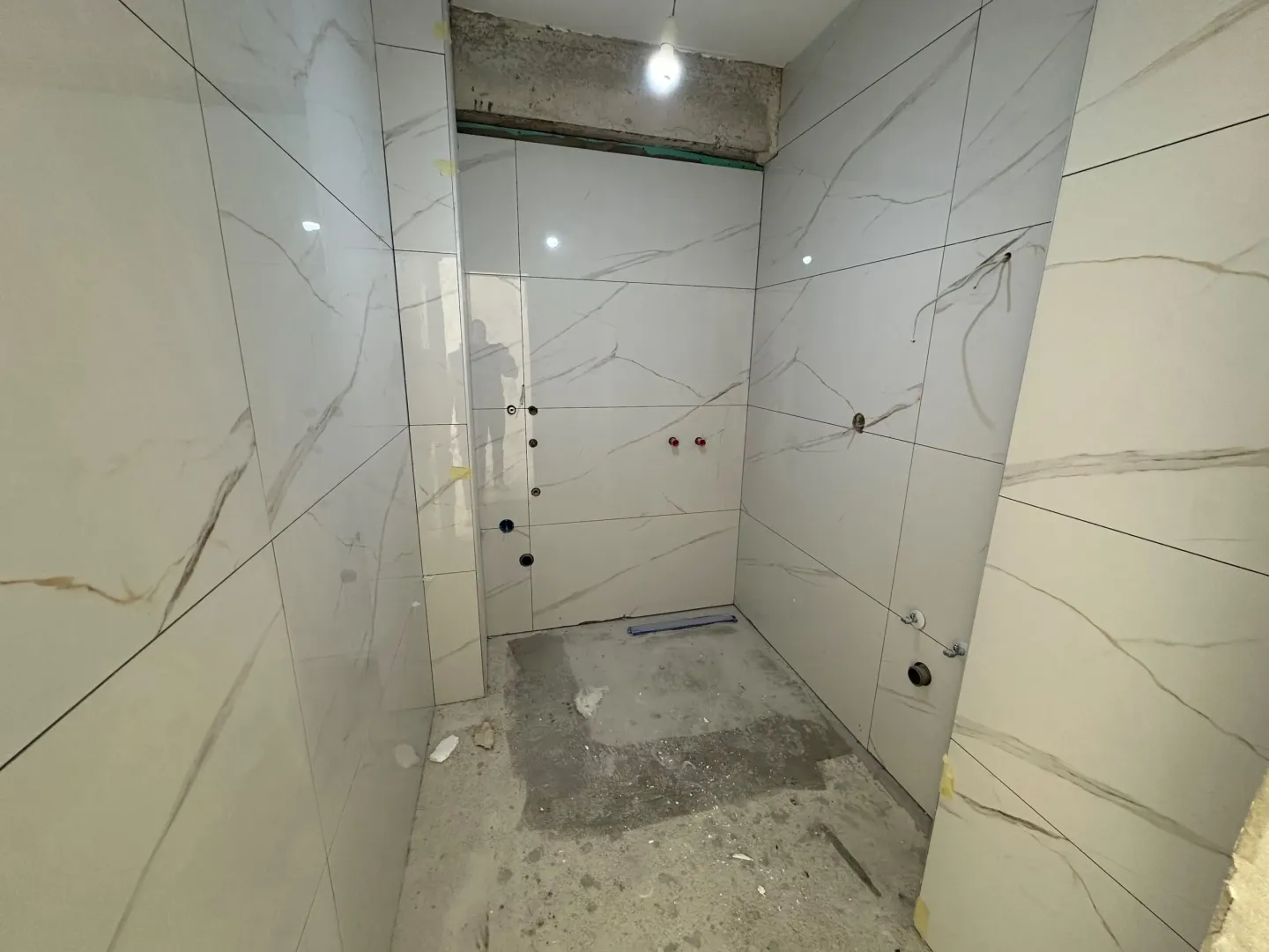 Bathroom under renovation with installed ceramic tiles and prepared plumbing.