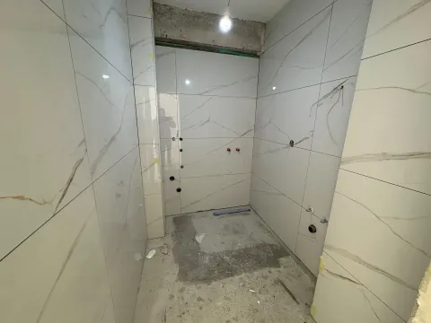 Bathroom under renovation with installed ceramic tiles and prepared plumbing. - image 5