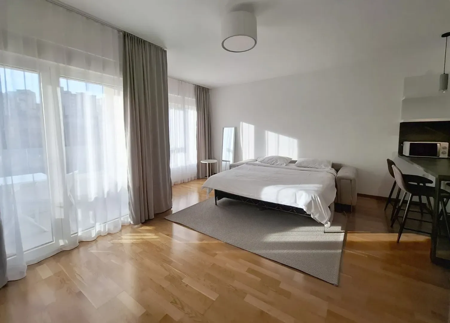 Bright bedroom with a double bed, wooden floor, and terrace access.