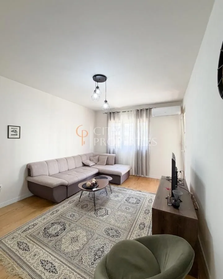 Dnevna soba sa garniturom, stočićem i televizorom.