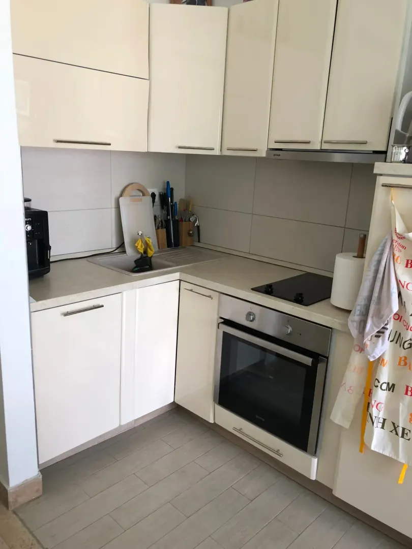 Compact kitchen with white cabinetry and a built-in oven.