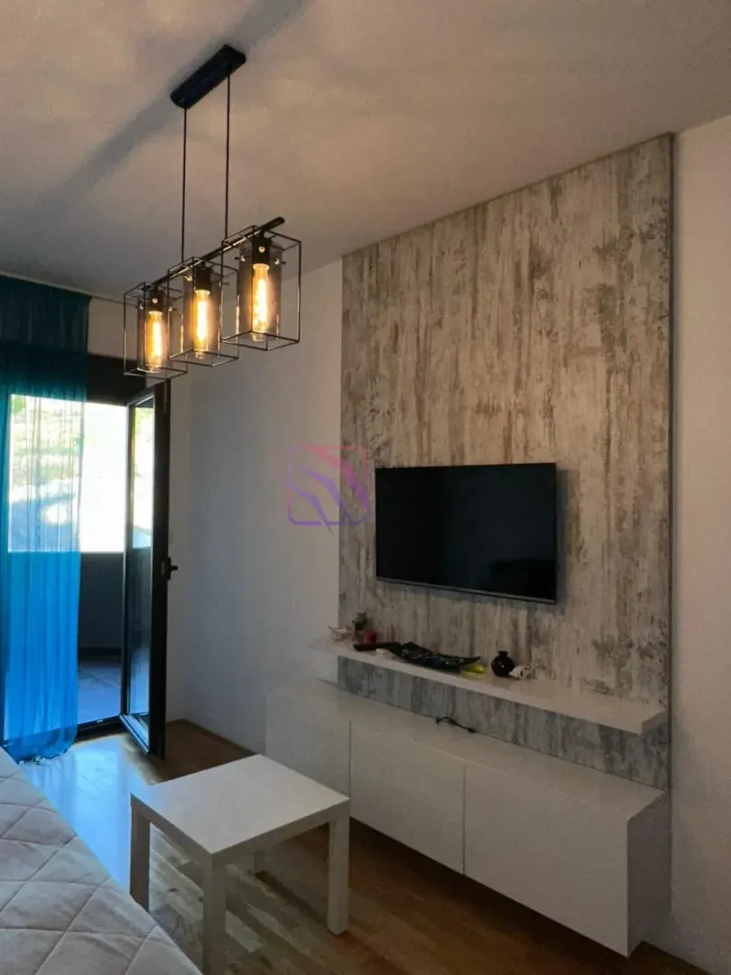 Dnevna soba sa TV policom i modernim lusterom.