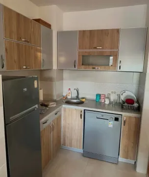 Compact kitchen with wooden cabinets, refrigerator, and dishwasher. - image 3