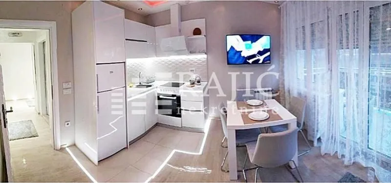 Modern white kitchen with a dining area and built-in appliances.