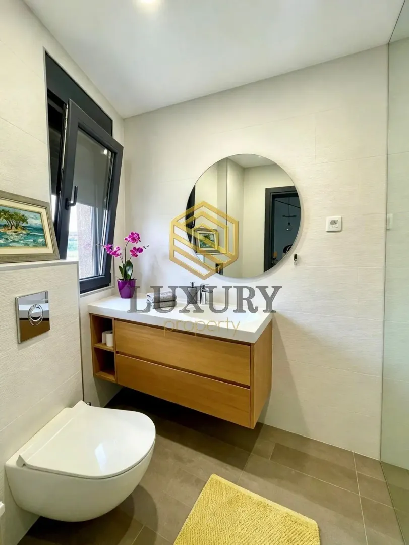 Modern bathroom with a sink, mirror, and toilet.
