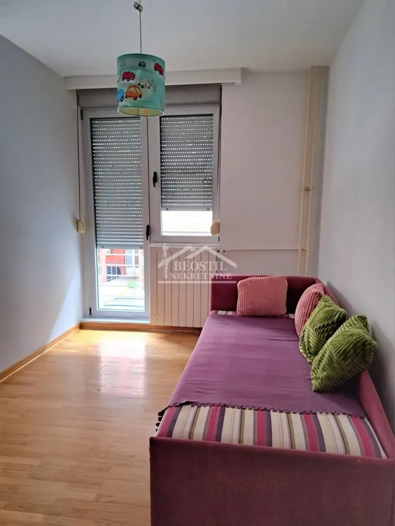 Manja spavaća soba sa krevetom i izlazom na terasu.