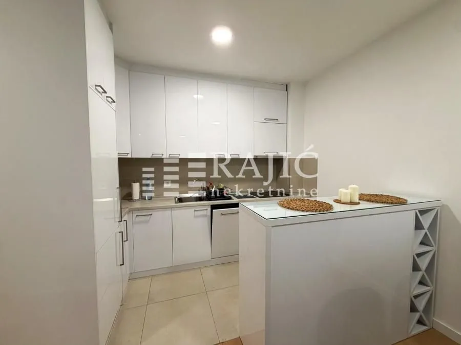 Modern white kitchen with a breakfast bar and built-in appliances.