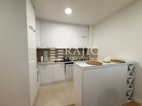 Modern white kitchen with a breakfast bar and built-in appliances. - image 7