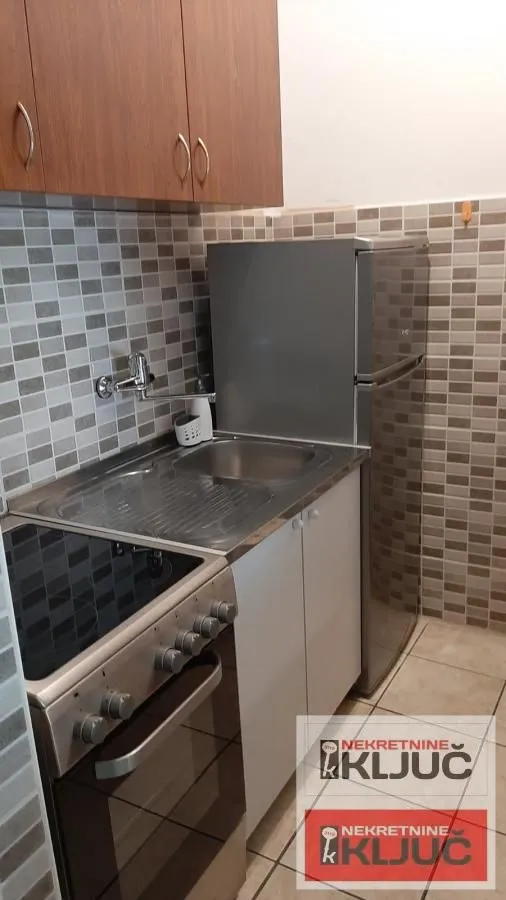 Manja kuhinja sa sudoperom, šporetom i frižiderom.