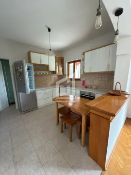 Kitchen with white cabinets, wooden details, and a dining table with chairs. - image 4
