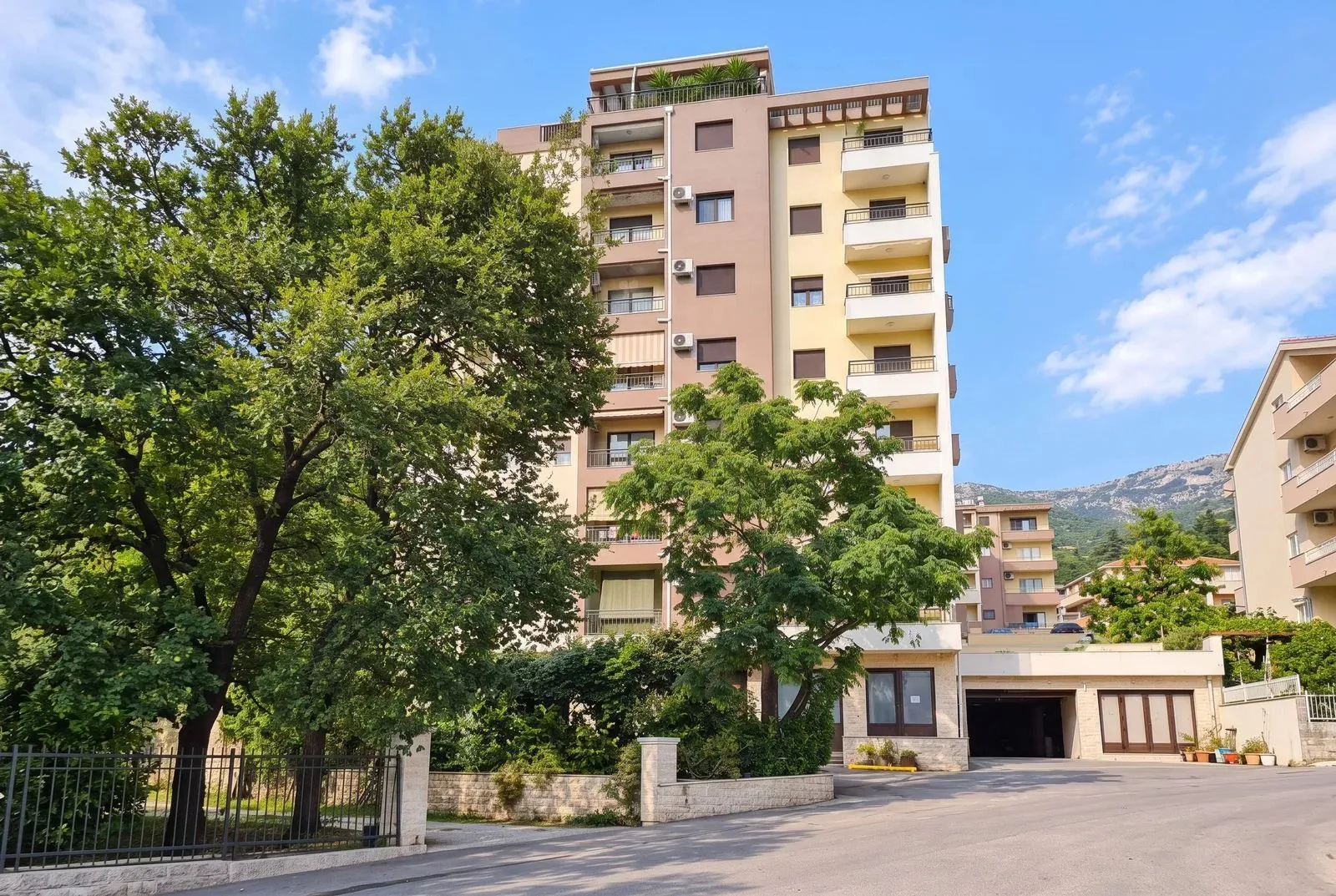 View of a multi-family residential building with landscaped surroundings and greenery.