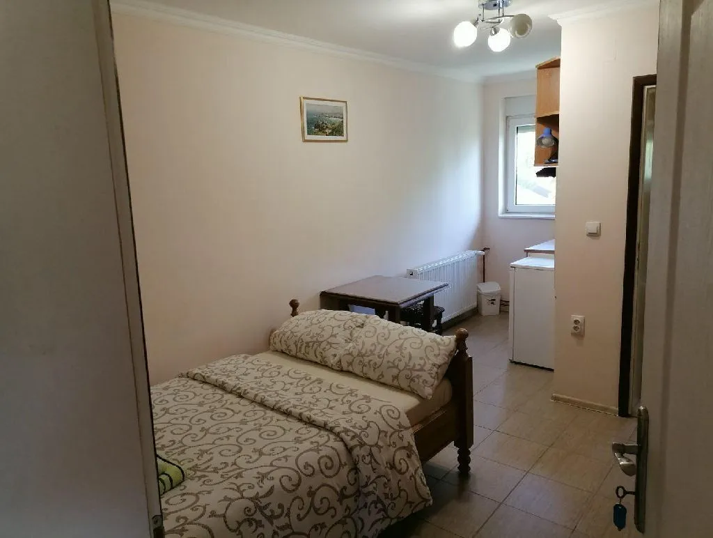 Manja spavaća soba sa bračnim krevetom i malim stolom.