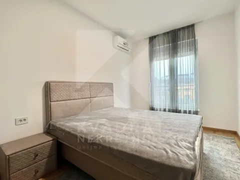 Furnished bedroom with a double bed, bedside table, and air conditioning unit. - image 9
