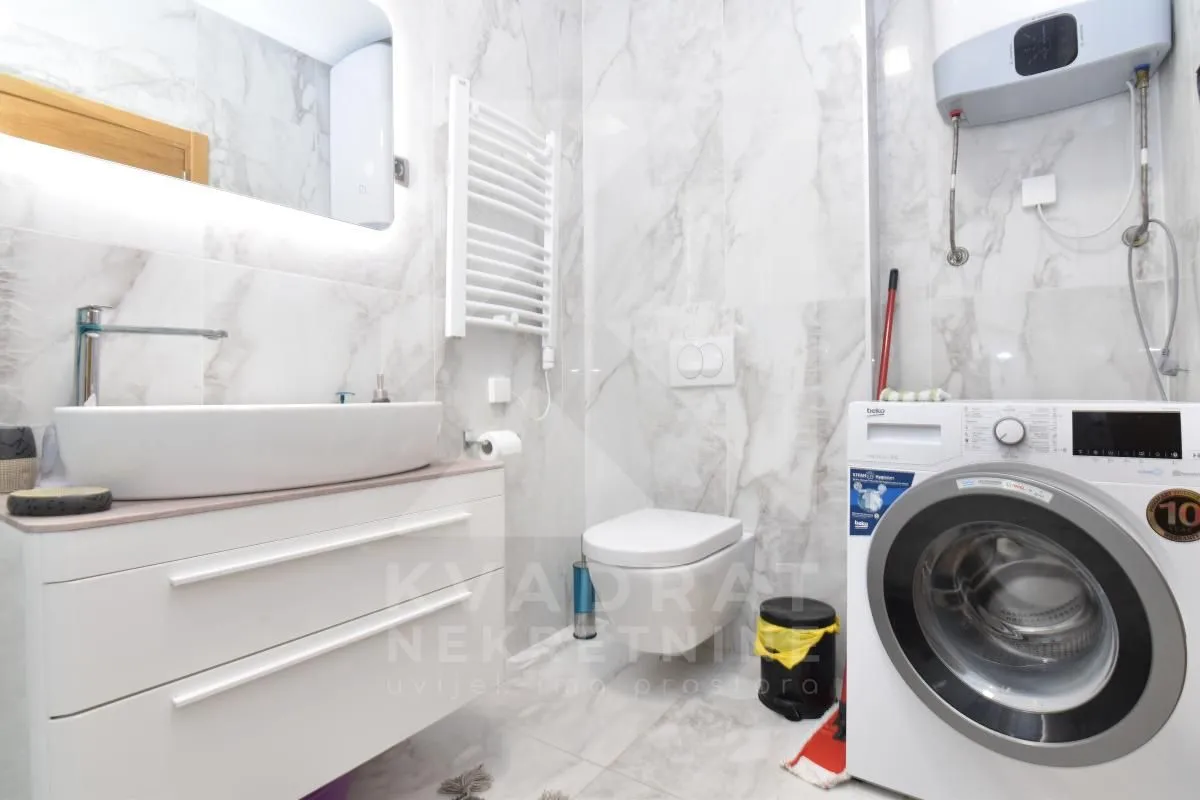 A modern bathroom equipped with a washbasin, toilet, and washing machine.