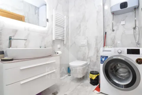 A modern bathroom equipped with a washbasin, toilet, and washing machine. - image 12