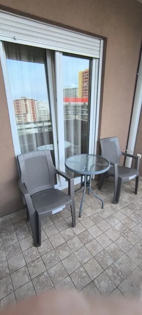 A balcony with two grey chairs and a small glass table.