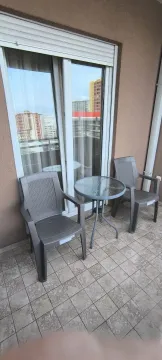 A balcony with two grey chairs and a small glass table. - image 19