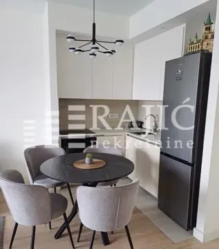 Dining area with a modern table and chairs and a kitchen in the background. - image 2
