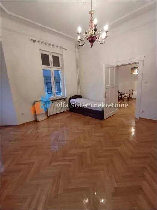 Spacious room with parquet flooring, a bed, and a chandelier.