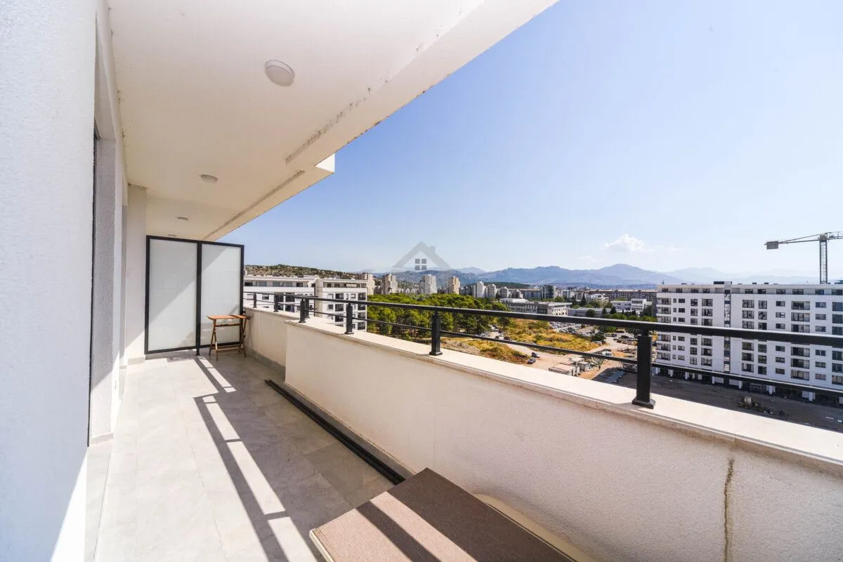 Spacious balcony with a view of the city and surrounding buildings.