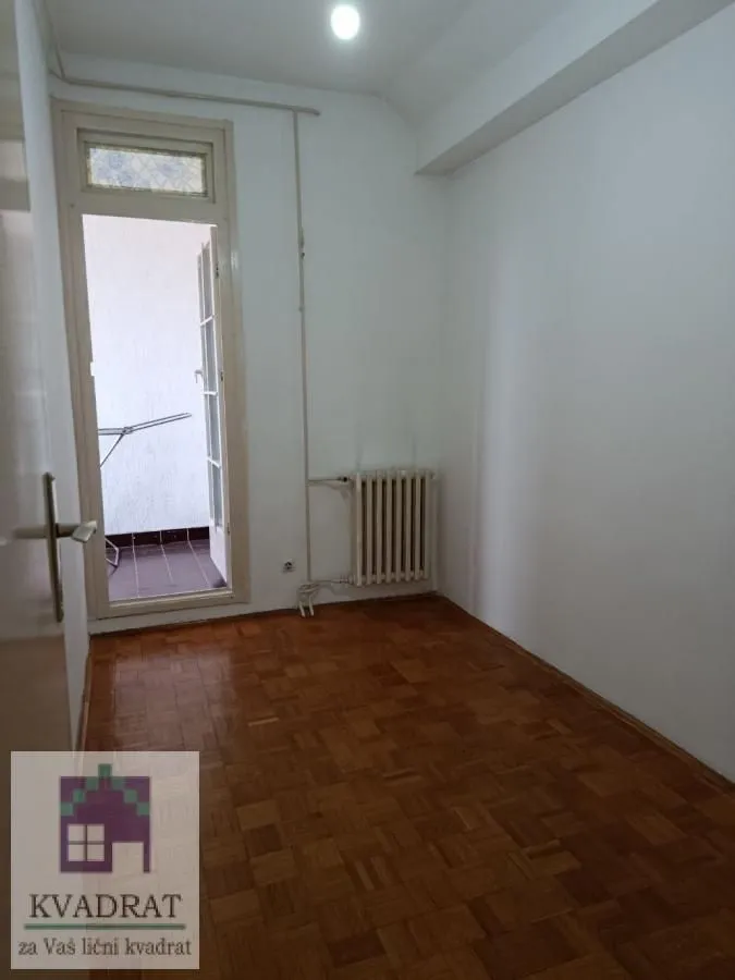 Prazna soba sa parketom i izlazom na balkon.